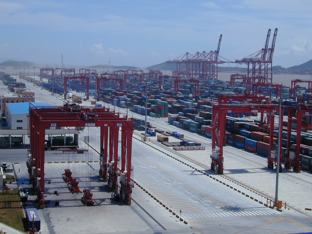 Stacked shipping containers and tall gantry cranes lining the quays of the Yangshan deep-water port near Shanghai.